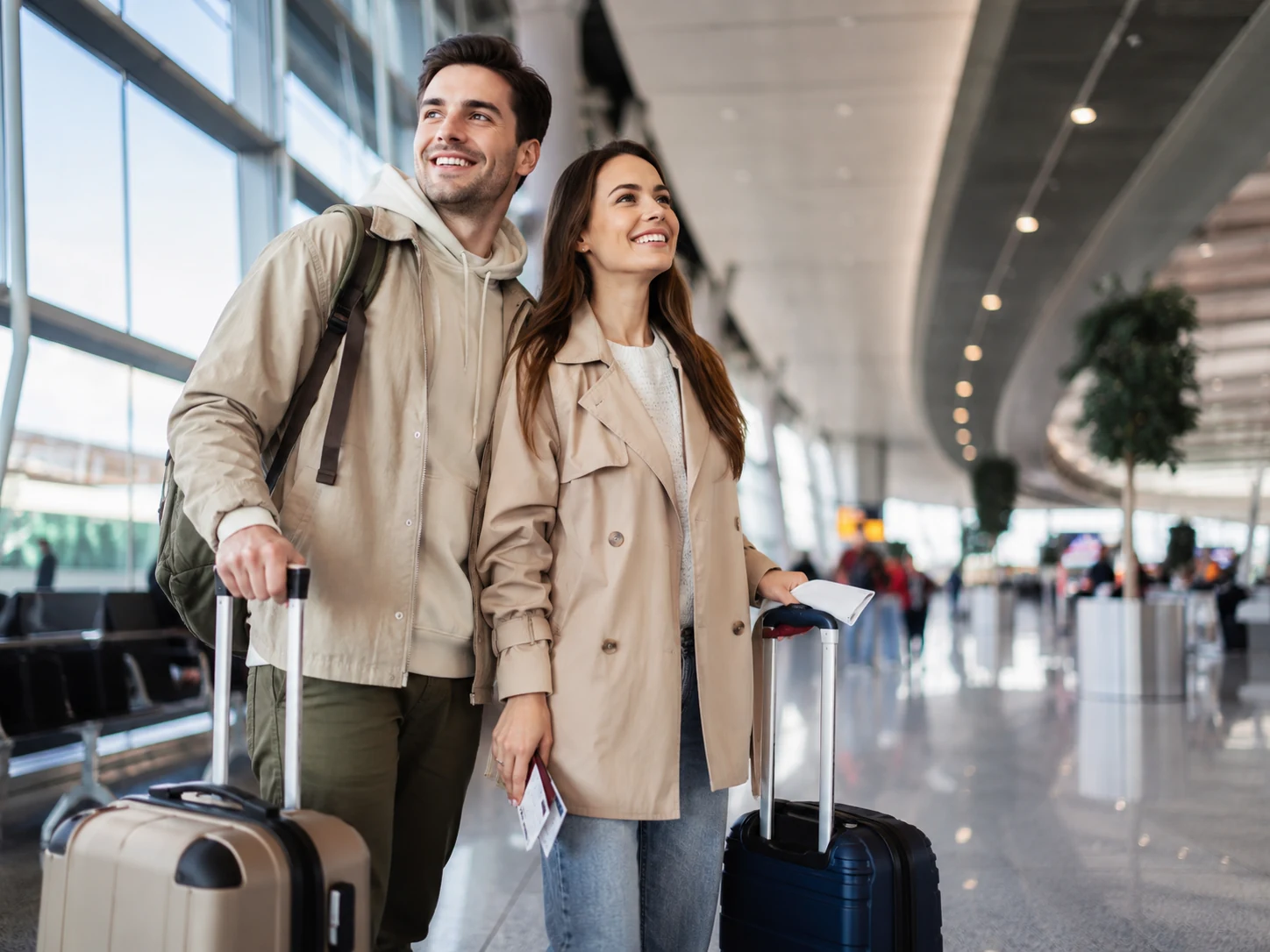 Couple with suitcases walking through a modern airport terminal